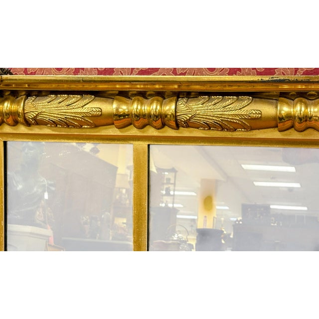 Ornate 19th-century American Federal-style overmantle mirror is constructed from giltwood with a gold finish. This triple-...