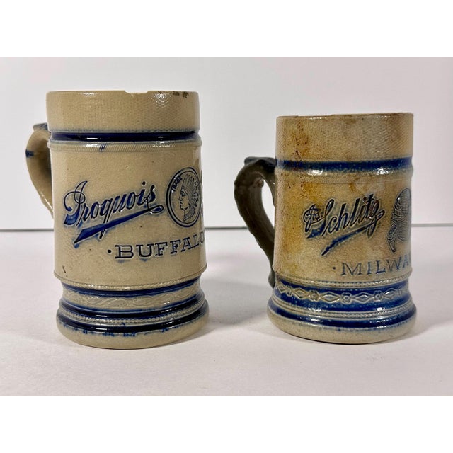 Pair of Antique Whites Utica Salt Glazed Stoneware Advertisement Beer Steins for your consideration. American, New York....