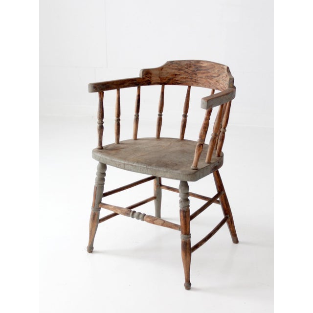 This late 19th-century captain's chair features a classic spindle-back form with a shaped crest rail, turned supports, and...