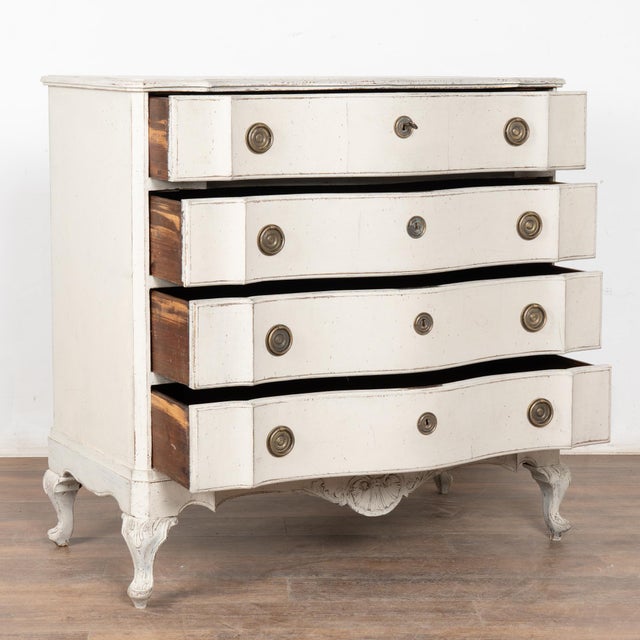 The white painted finish is striking in this attractive large chest of four drawers resting on a decoratively carved skirt...