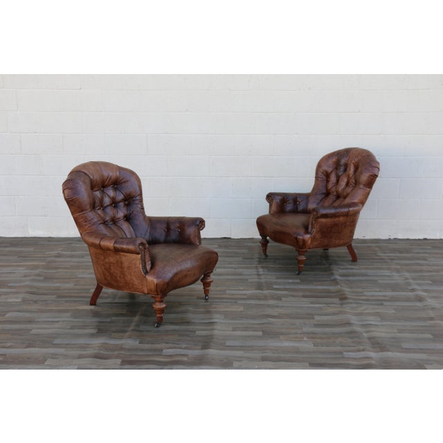 A handsome pair of vintage 1980s brown leather library armchairs, featuring beautifully distressed leather with a rich,...