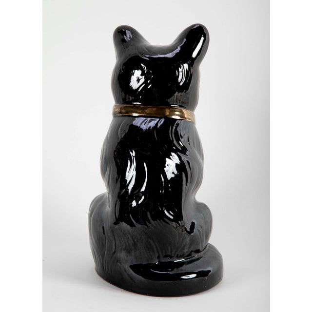 A charming seated glazed ceramic black cat with yellow glass eyes and gilt bow around neck. What I find most appealing...