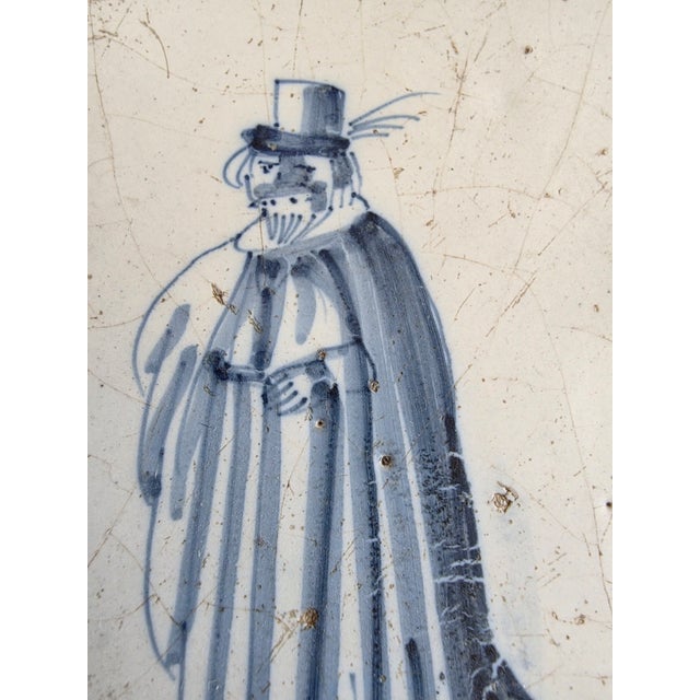 Early delft tile with a haunting figure of a man and corner decoration. The frame is from the 1960's and appears to be cut...