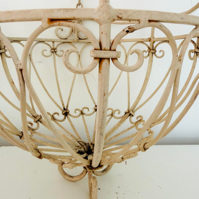 Pair of vintage painted wrought iron hanging plant holders. Each is approximately 12" in diameter, 11" in height, and 24"...