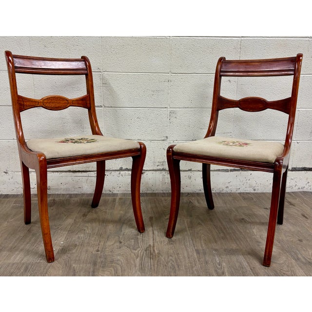 This is a beautiful antique pair of Regency / Duncan Phyfe style dining chairs featuring elegant saber legs, decorative...