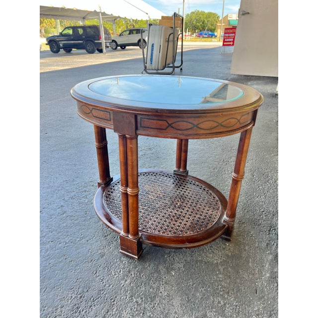 Vintage glass top oval table. Wood table with glass insert and cane weaved bottom level. Cane weave bottom. It is fully...