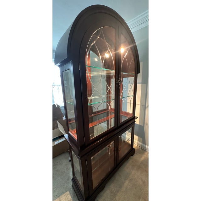 Philip Reinisch Cherry-finished Curio with Beveled Glass Doors. This is a lighted cabinet with glass shelves, 4 doors and...