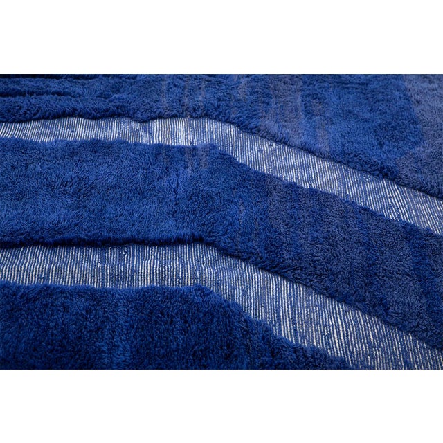 A deep royal blue field traced with pale, meandering ivory lines — abstract markings that feel almost calligraphic against...