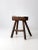 An antique primitive wooden stool featuring a distinctive saddle-shaped seat and splayed legs. Its simple construction and...