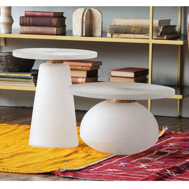The white-frosted Glass Low Table features a round tabletop with a squat, bulbous base. The tabletop is ridged with...