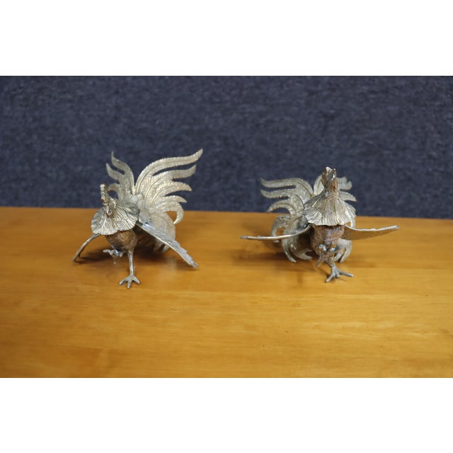 Striking pair of vintage brass rooster figurines, finely detailed with expressive plumage, raised wings, and flowing tail...