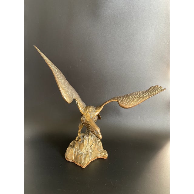 A striking Mid-Century brass sculpture featuring an eagle landing on a rock. The piece is in nice condition, showing...