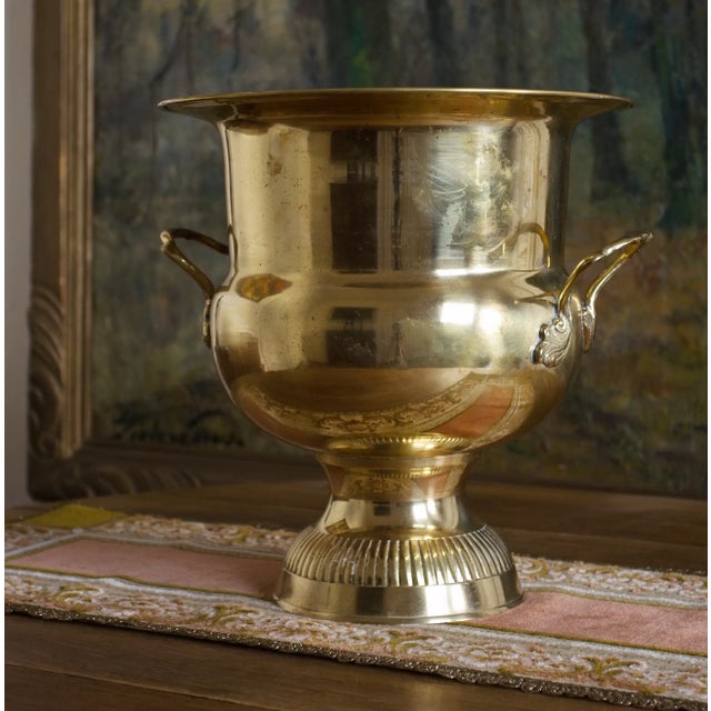 Representative large-format champagne cooler, also suitable for Magnum bottles. The polished brass container has a wide-...