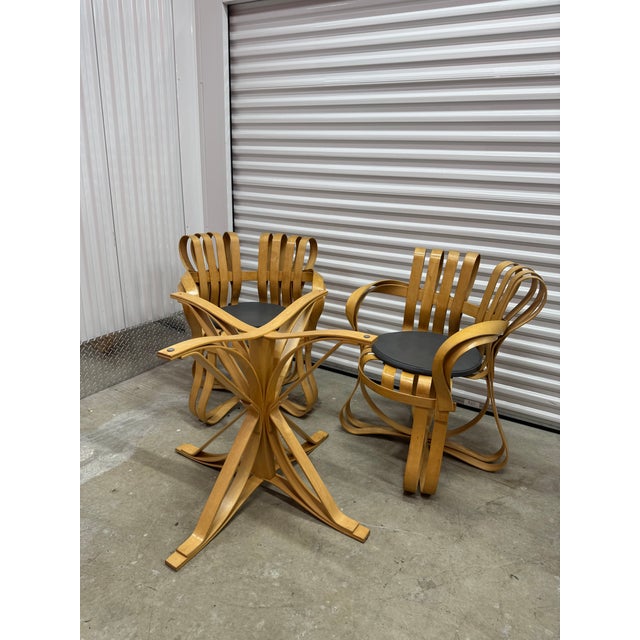 Distinctive and sculptural, this dining set by Frank Gehry includes two Cross Check chairs and one Face Off table,...