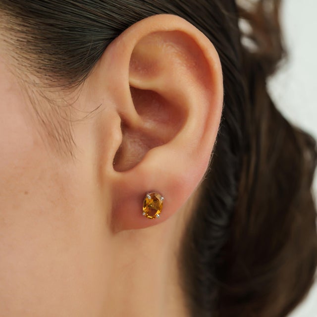 The Classic Luxe Oval Citrine Stud Earrings feature a combined gemstone weight of 1.49 carats, showcasing faceted oval...