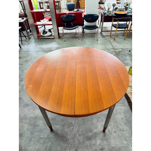 Extendable round table with teak top and legs and satin-finish metal legs, 1960s. Extension system with a sliding central...