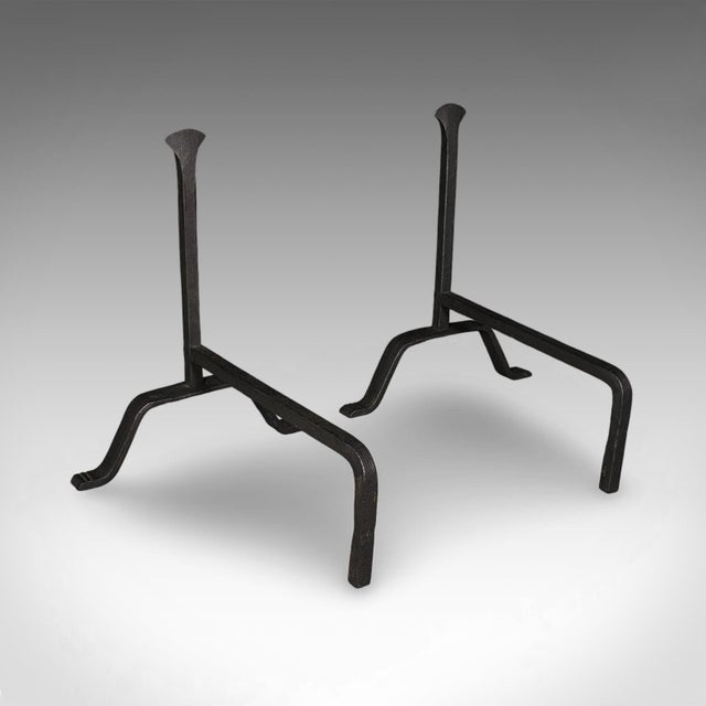This is a pair of antique fire dogs. An English, wrought iron fireplace andiron, dating to the Victorian period, circa...