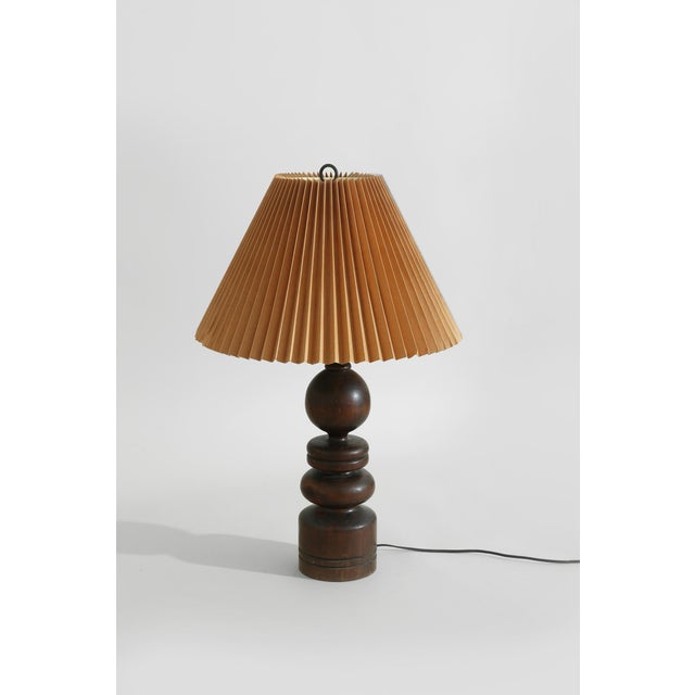 A sculptural table lamp crafted from richly grained turned wood, featuring a stacked series of rounded geometric forms....