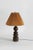 A sculptural table lamp crafted from richly grained turned wood, featuring a stacked series of rounded geometric forms....