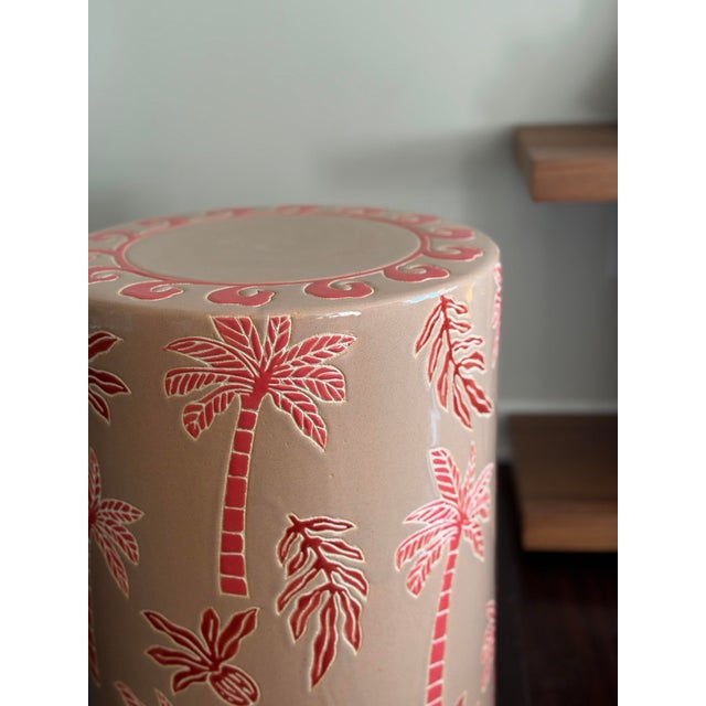 A one-of-a-kind ceramic stool by Made Goods, featuring a tropical palm motif in soft blush and layered reds. This glazed...
