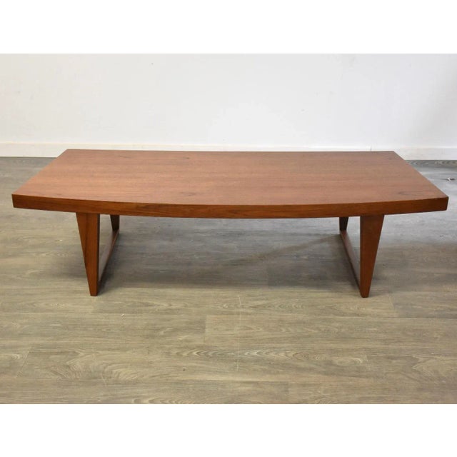 A mid century modern teak curved coffee table with a sled base. Professionally refinished. 66.25” wide. 25.125” deep....