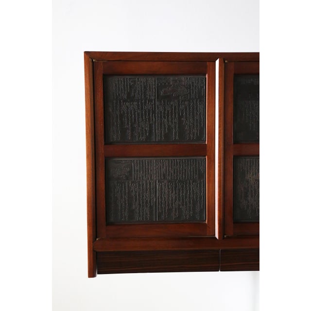 A wall mounted floating credenza consisting of a walnut case, 4 doors accentuated with Chinese printers block and an...