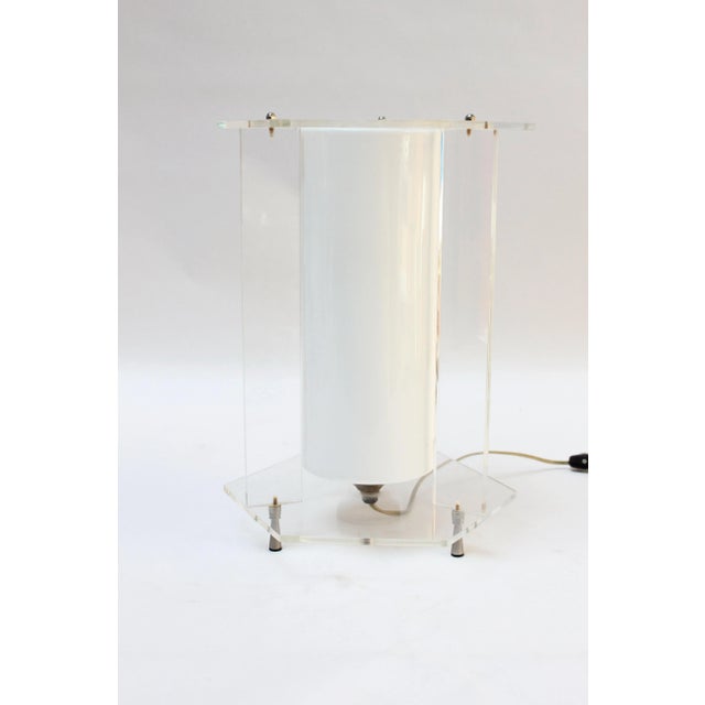 Acrylic hexagonal-form table lamp with a white cased-glass inset cylinder, all supported by three conical metal feet (ca....