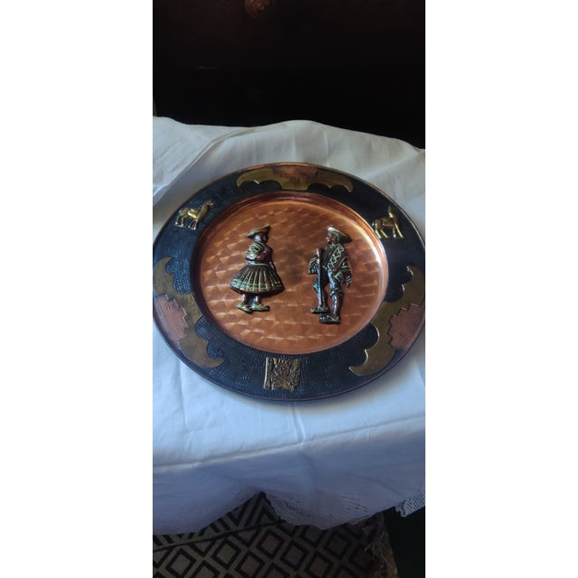 Decorative copper metal brass wall plate. The quotidian campesino couple in the center. Lana, and Aztec emblem.