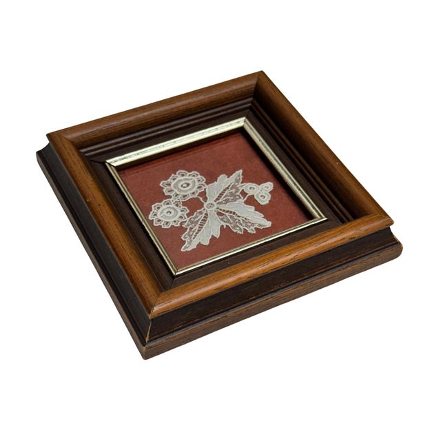 Delicate vintage textile artwork featuring a piece of handmade Belgian lace arranged in an intricate botanical composition...
