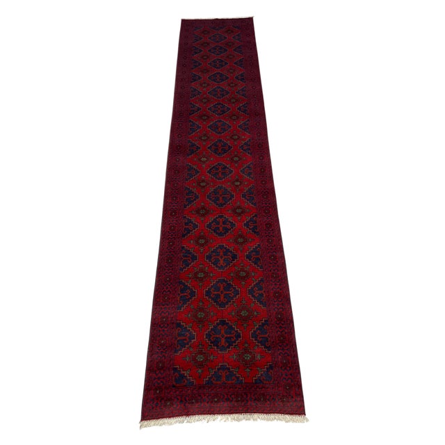 A repeating row of navy blue geometric medallions runs through the vivid red field of this wool runner. Smaller motifs and...