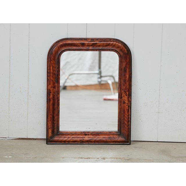 A small French Louis-Philippe style wooden mirror from the early 20th century, with faux tortoise style painted frame and...