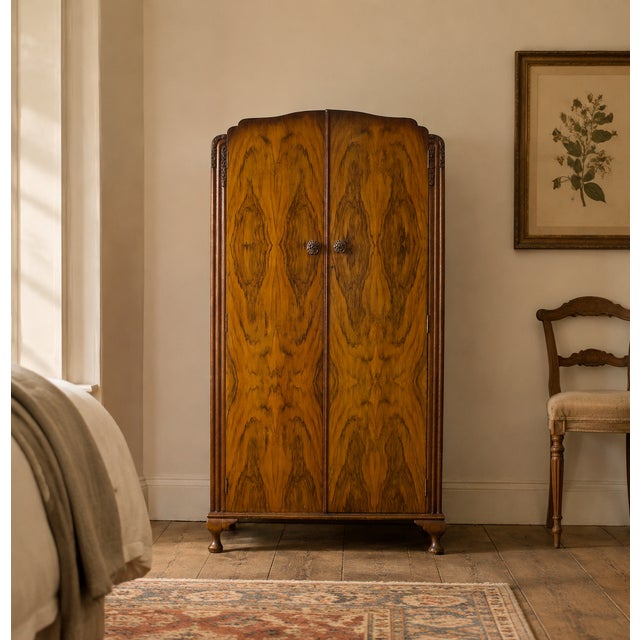 An elegant 1930s Art Deco wardrobe in beautifully figured walnut, with carved floral detailing, original handles and...