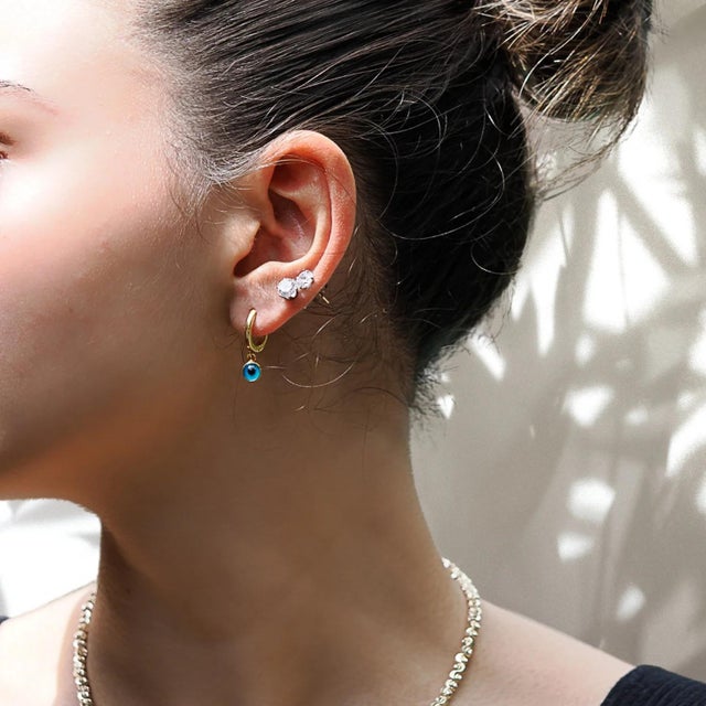 The Gold Huggie Hoop Earrings are designed in a classic huggie hoop style, which is known for its comfortable fit and...