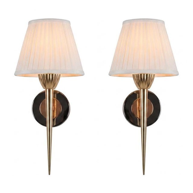 Pair of wall lights dating to the 1950s. Each has a fluted brass cup beneath the bulb holder and a long, tapering pointed...