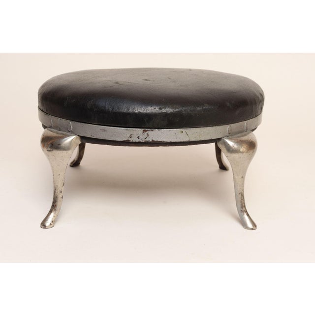 Art Deco cast metal foot stool with cabriole legs and leather upholstery (ca. 1940s, USA). A stylish interpretation of a...