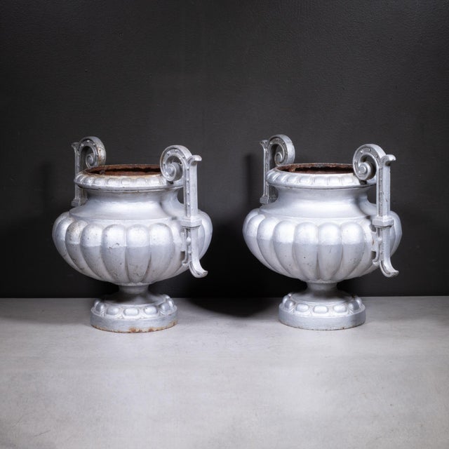 ABOUT A pair of 19th-century French cast iron garden urns featuring a classic lobed lower bowls, flared rims, and a...
