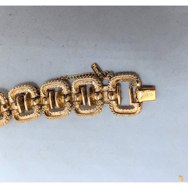 1974 textured goldtone link bracelet with fold over clasp and security chain. Marked "MONET©" on the back of the clasp and...