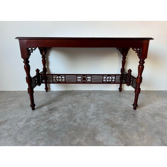 A beautifully crafted vintage Chinese console table made from solid mahogany, showcasing elegant hand-carved details and...