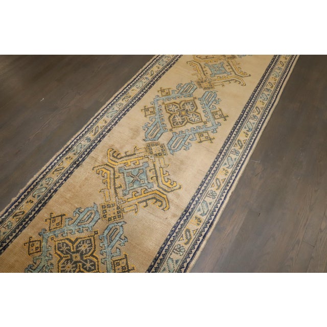 An authentic antique oushak runner. Accents in powder blue and mustard on a bone colored field and border. 3'1'' x 17'5''