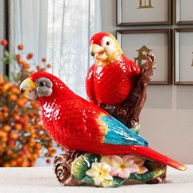 This vibrant porcelain figurine depicts a pair of parrots perched together on a sculpted branch. The birds are finely...