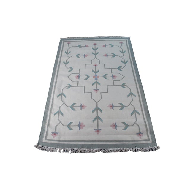 This Vintage Hand Woven Indian Dhurrie Area Rug showcases a minimalist and airy aesthetic, combining a clean cream...