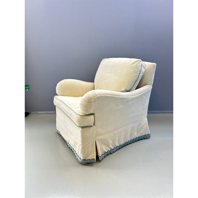 Armchair upholstered in cream velvet with blue piping. Very comfortable. This piece is attributed to the mentioned...