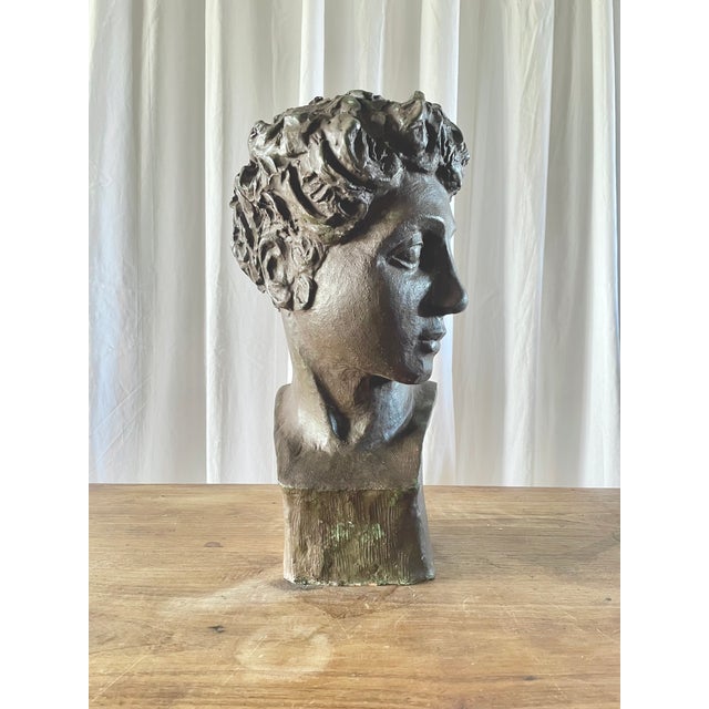 A male bust in terracotta with a bronze patina, inspired by antiquity and possessing a strong sculptural character. This...