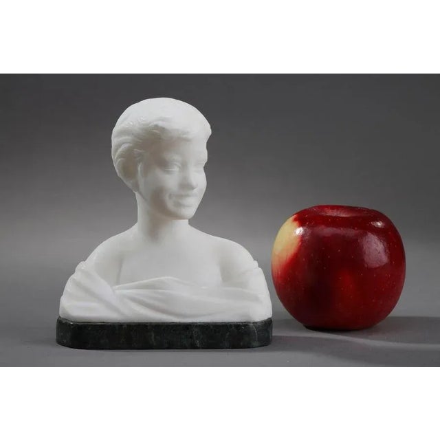 Small alabaster bust representing a young boy wearing a drape. This very lively statuette shows him talking while turning...