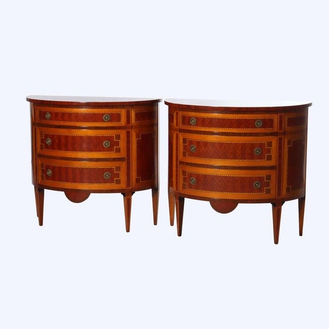 A sophisticated pair of Italian Hepplewhite style demilune cabinets, imported by Decorative Crafts Inc., crafted in the...