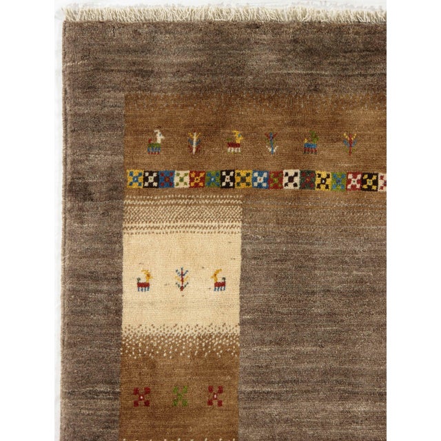 Vintage Hand-knotted Persian Lori Gabbeh rug featuring a soft brown field framed by a wide, multi-band border with...