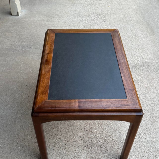 Beautiful vintage Mid-Century Modern coffee table featuring sculpted walnut construction and a recessed black laminate...