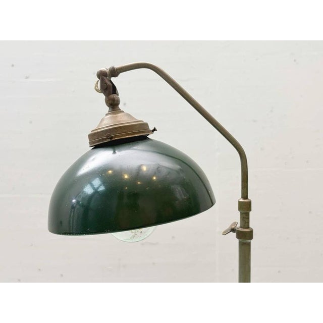 Compact table lamp in a functional industrial style with a heavy metal base, tall adjustable stem, and characteristic...