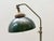 Compact table lamp in a functional industrial style with a heavy metal base, tall adjustable stem, and characteristic...