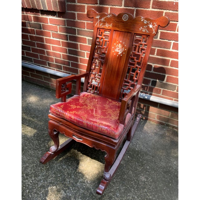 A large carved rosewood chinoiserie rocking chair with a colorful pad. Can be used as an accent chair or a side chair....